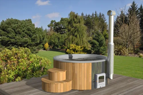 Hot Pot in grau mit Treppeneinstieg auf einer Terrasse aus Holz in einem grossen Garten.